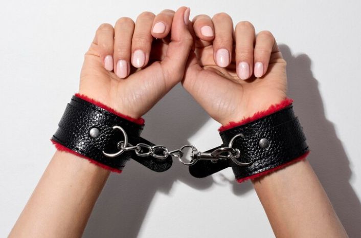 Leather BDSM handcuffs worn by a lady